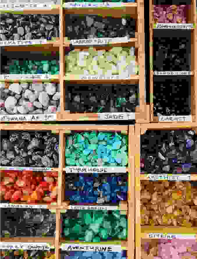 An assortment of different coloured gemstone in boxes