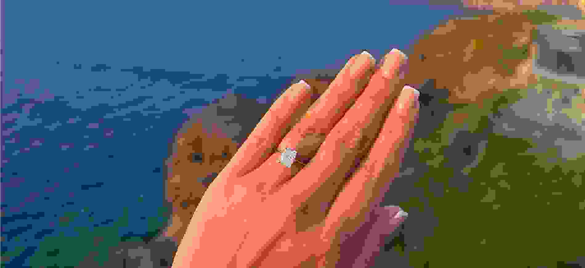 Engagement ring up close with a costal scene in the backgorund