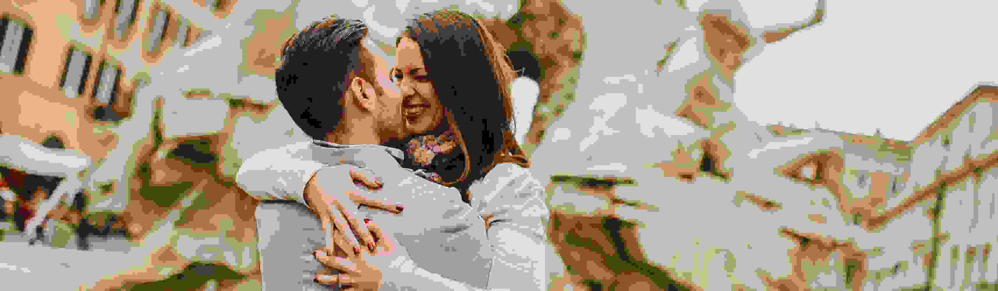 Happy couple embracing and smiling in front of a historic fountain in a European city, celebrating a romantic moment together