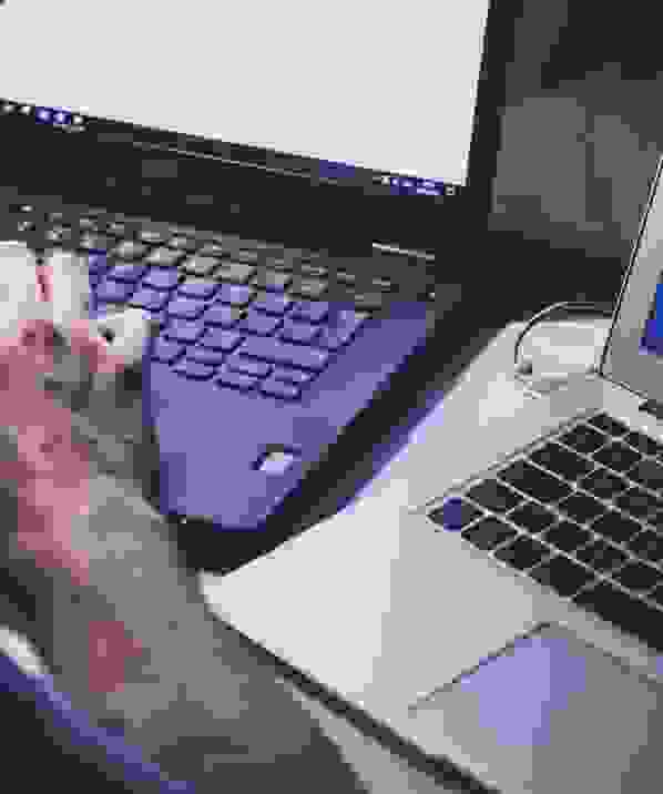 Close-up of a person working on a laptop next to another open laptop, suggesting online activity or browsing.