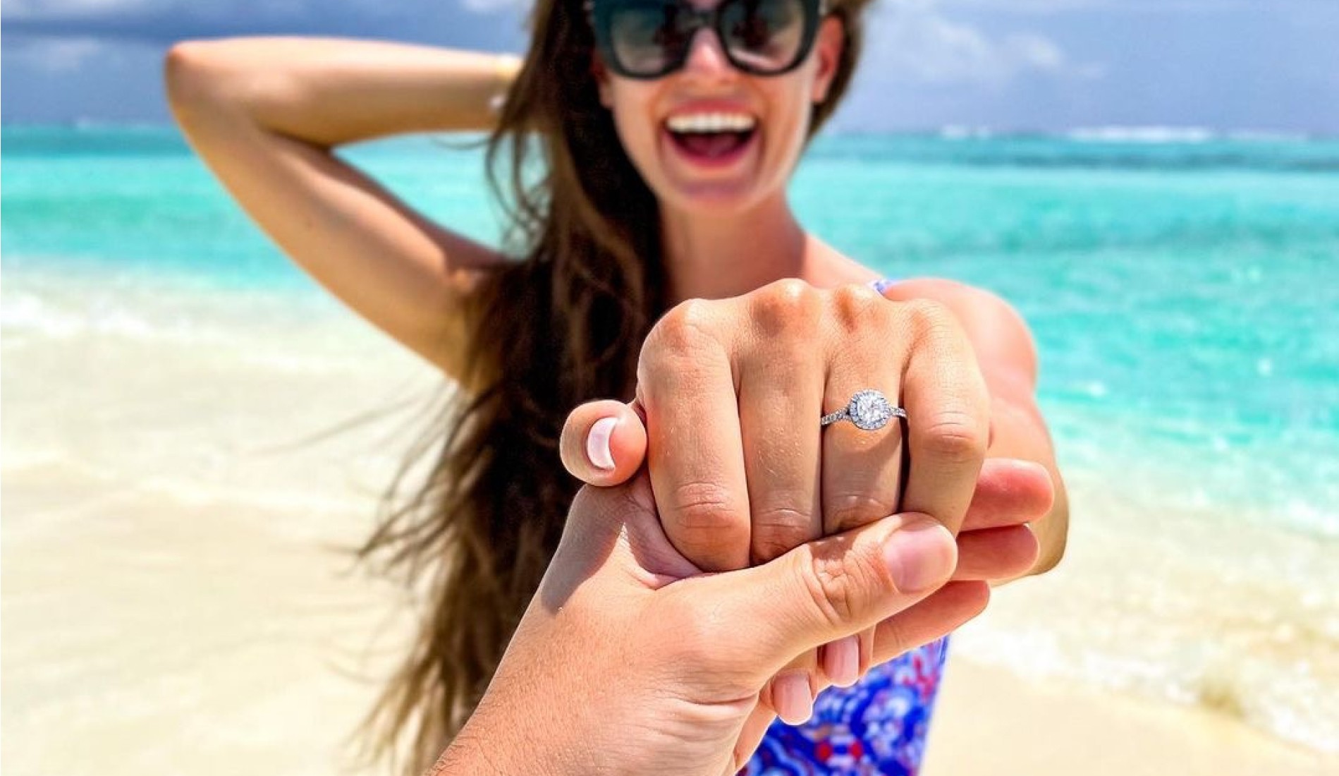 Engagment ring on womans hand on a beach