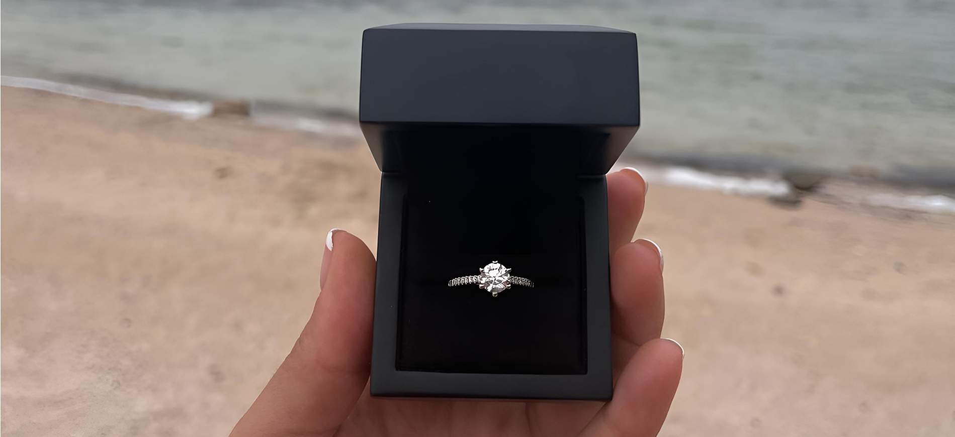 Engagement ring in a box on a beach