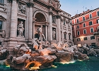 Trevi Fountain in Rome illuminated at dusk, with intricate sculptures and flowing water in the foreground