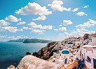 Picturesque view of white-washed buildings with blue domes on the cliffs of Santorini overlooking the Aegean Sea.