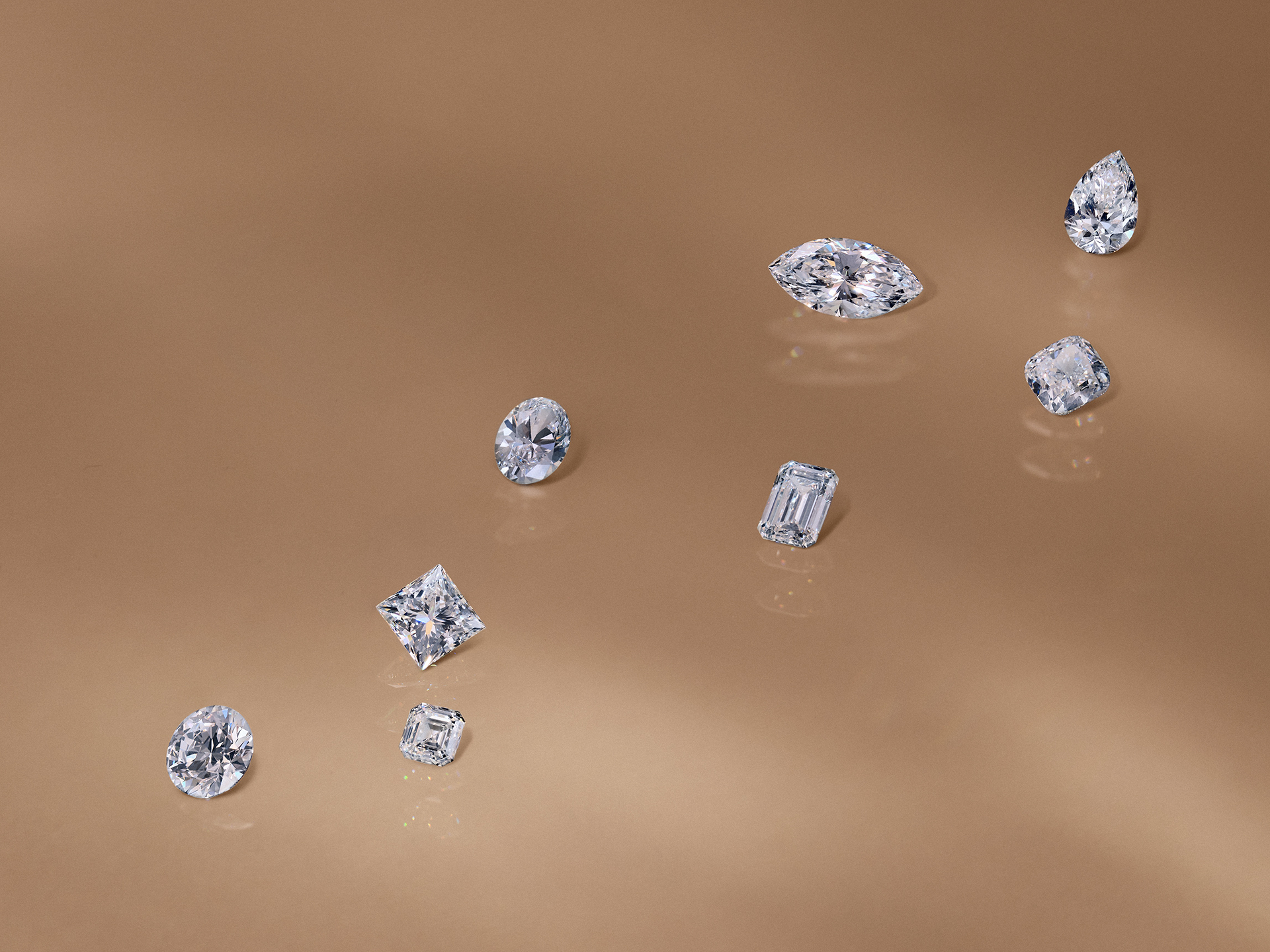 Sortiment zářivých volných diamantů v různých brusech: hruškový, markýzový, oválný, smaragdový, Princess, polštářový.
