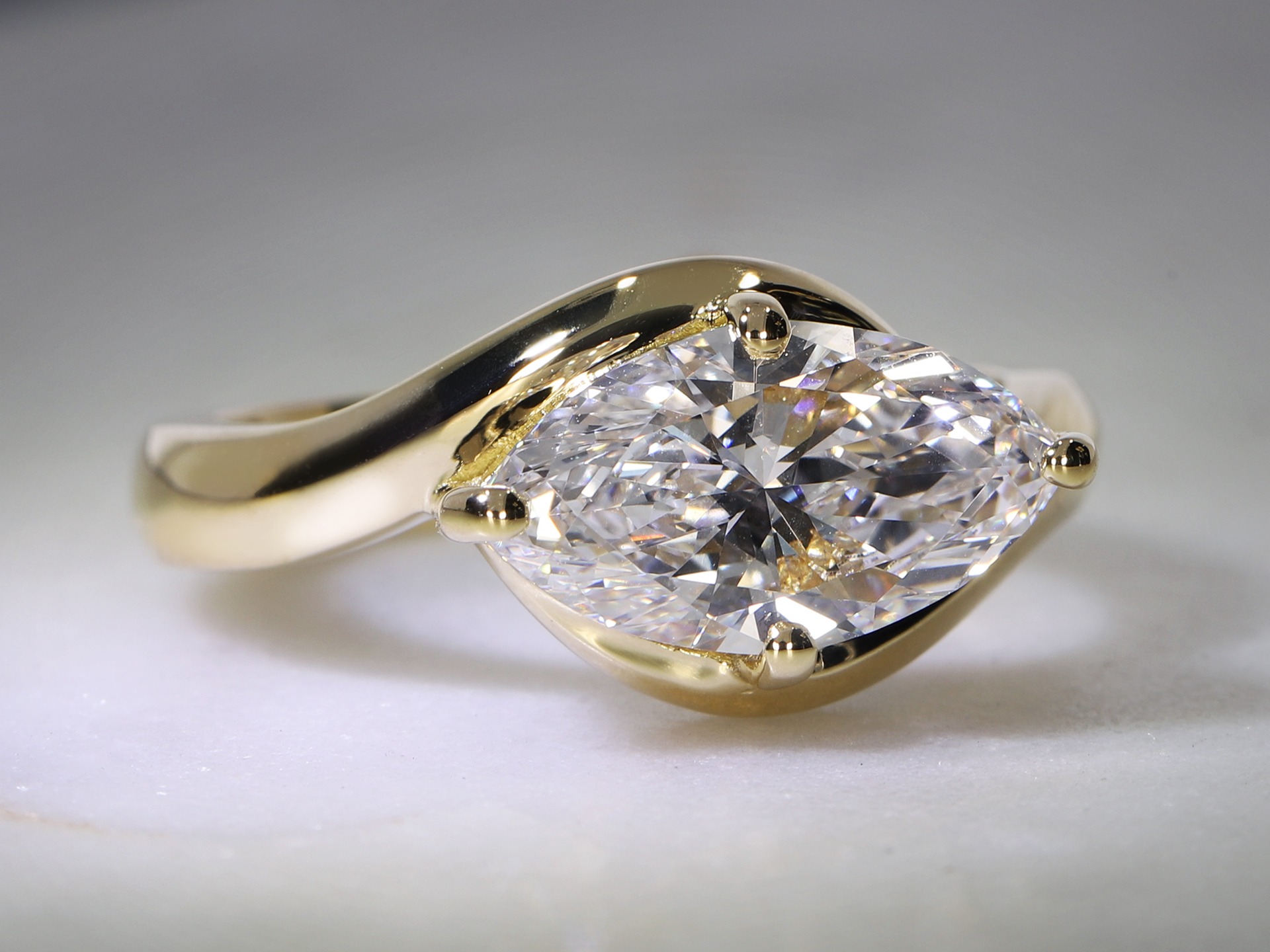 Primo piano di un anello di fidanzamento con diamante brillante taglio marquise in una montatura bypass in Oro giallo.