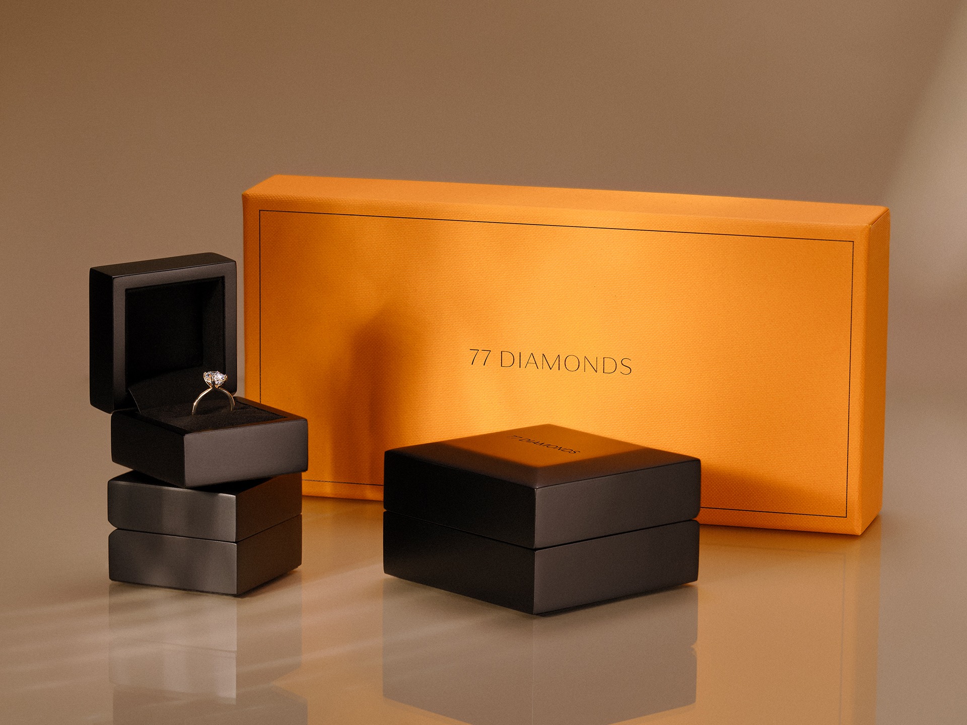 77 Diamanti confezioni di lusso: scatola aperta con anello di diamanti, scatole nere, scatola regalo arancione.
