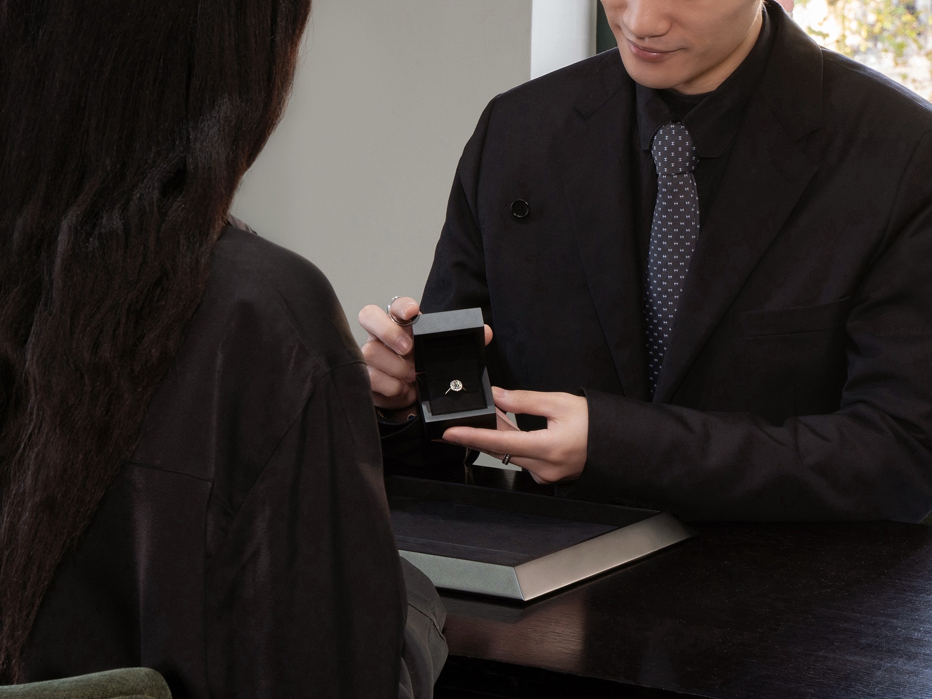 Esperto di gioielli che presenta una scatola aperta con un anello di diamanti ad un cliente.